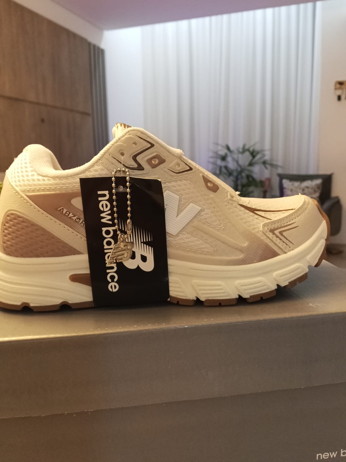 Tênis New Balance branco e bege com etiqueta da marca