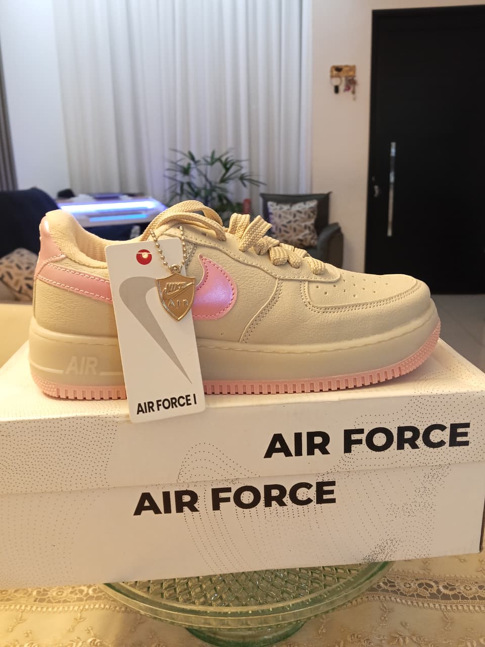 Tênis Nike Air Force bege e rosa sobre a caixa do produto